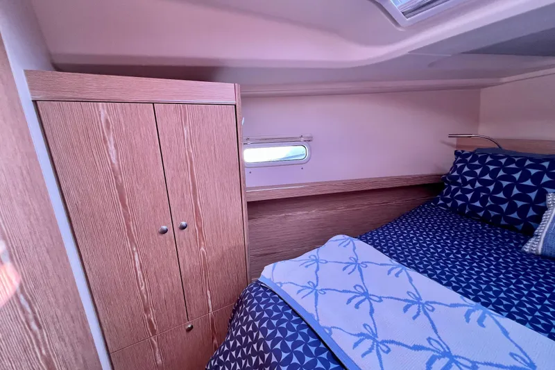 Slide: The Image of Cozy cabin interior of 2016 Hanse 455 yacht with wooden wardrobe and patterned bedding. - 163