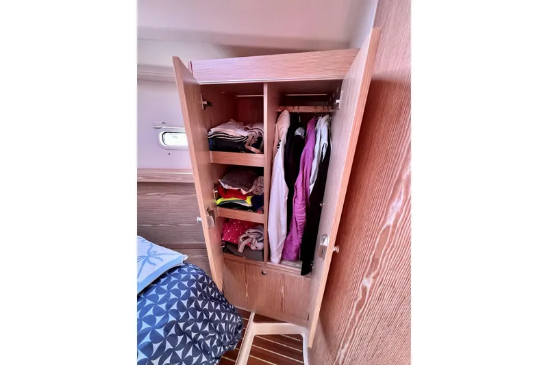 Slide: The Image of Wooden wardrobe with clothes inside a 2016 Hanse 455 yacht cabin. - 168