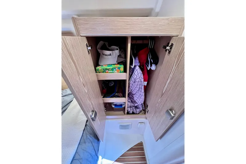 Slide: The Image of Open wooden wardrobe on 2016 Hanse 455 yacht, storing clothes and accessories. - 174