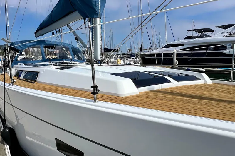 Slide: The Image of 2016 Hanse 455 yacht with sleek design, docked in a marina, featuring a wooden deck. - 22
