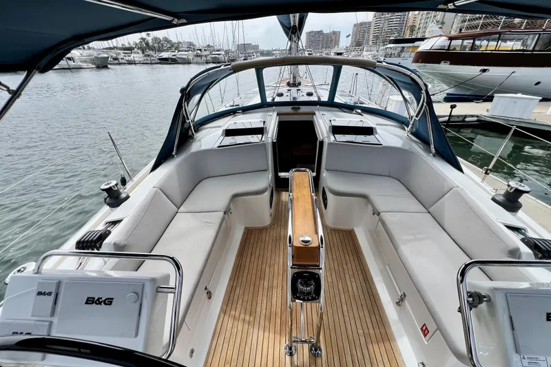 Slide: The Image of 2016 Hanse 455 yacht cockpit with teak flooring, white seating, and marina view. - 49