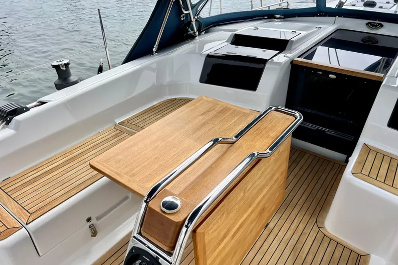 Slide: The Image of Cockpit of 2016 Hanse 455 yacht with wooden table and seating, docked by water. - 58