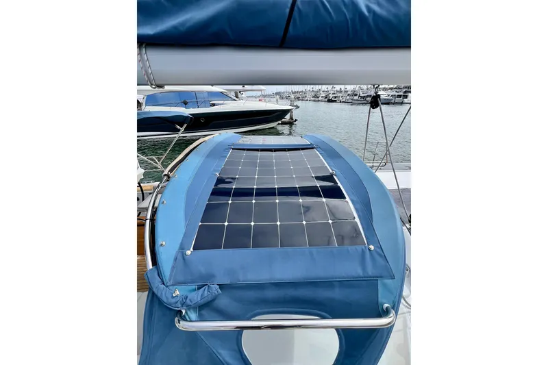 Slide: The Image of 2016 Hanse 455 yacht with solar panels on blue canvas, docked at marina. - 98