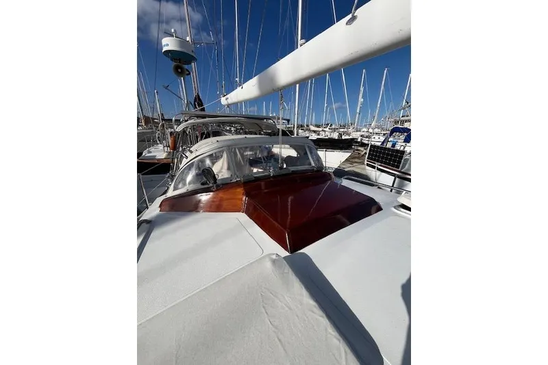 Slide: The Image of 1994 Hutting 40' sailboat with wooden accents docked in a marina under clear blue skies. - 11