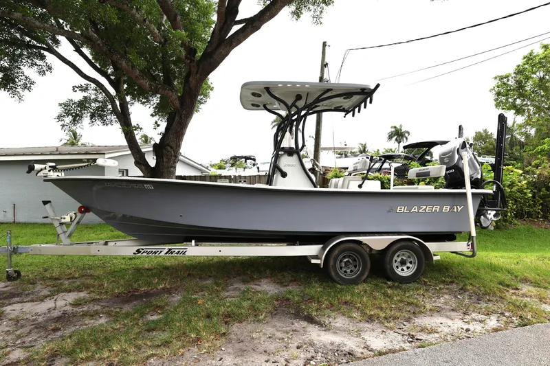 The Image of 2021 Blazer Bay 2400 boat on trailer, parked outdoors under a tree. - 0