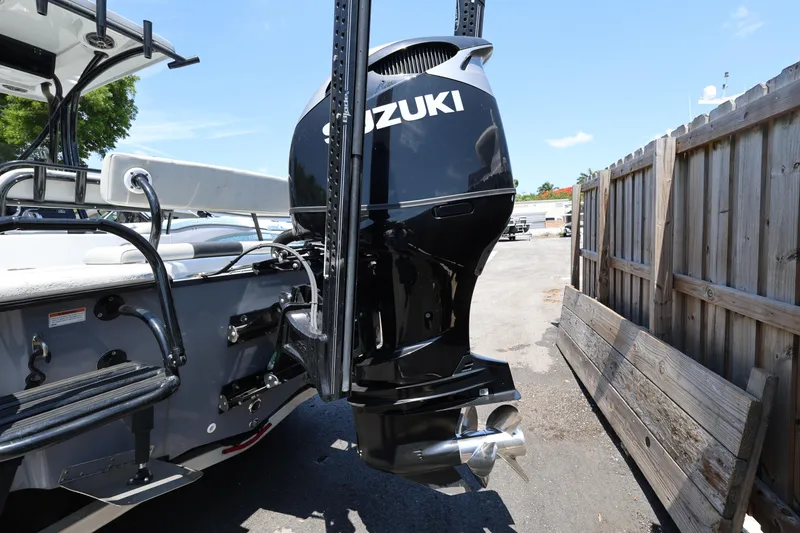 Slide: The Image of 2021 Blazer Bay 2400 boat with Suzuki outboard motor, parked near wooden fence. - 11