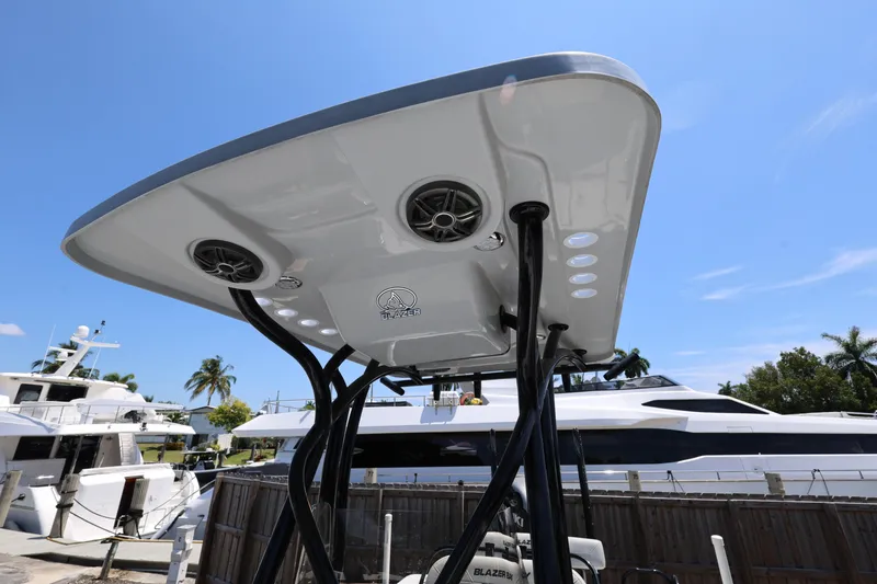 Slide: The Image of 2021 Blazer Bay 2400 boat with T-top speakers and lights, docked near yachts. - 25