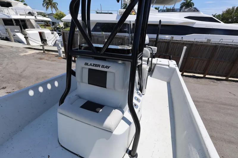 Slide: The Image of 2021 Blazer Bay 2400 boat interior with seating and console, docked near luxury yachts. - 26