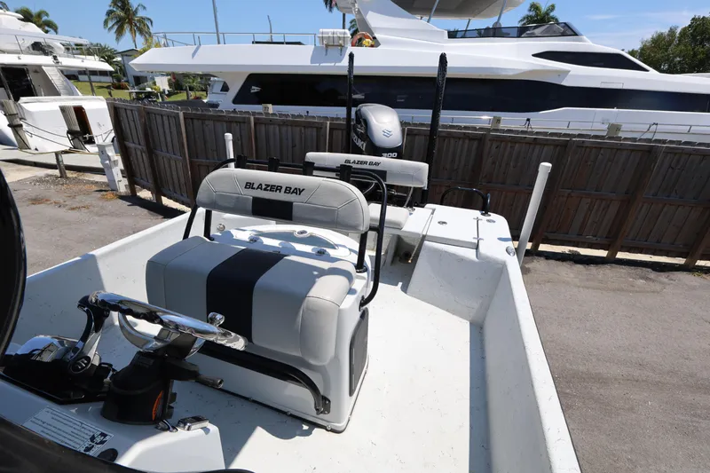 Slide: The Image of 2021 Blazer Bay 2400 boat interior with steering wheel and seating, docked near yachts. - 27