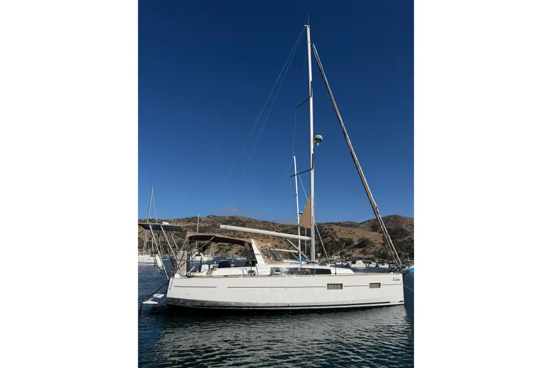 The Image of 2017 Beneteau Oceanis 38 sailboat anchored in a scenic coastal bay. - 0