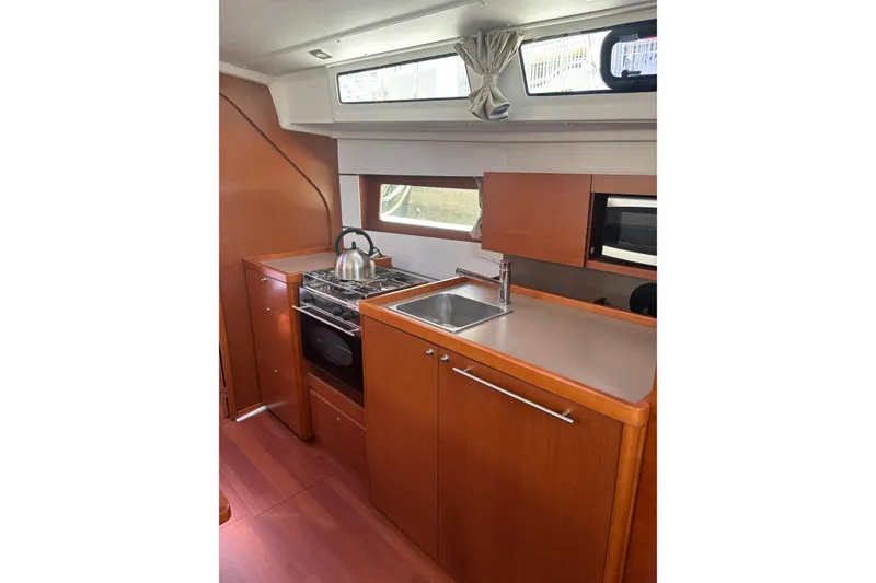 Slide: The Image of Interior view of 2017 Beneteau Oceanis 38 yacht kitchen with stove, sink, and cabinetry. - 26