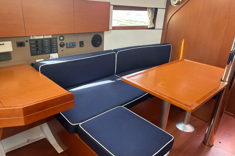 Slide: The Image of Interior of 2017 Beneteau Oceanis 38 sailboat with wooden table and navy seating. - 27