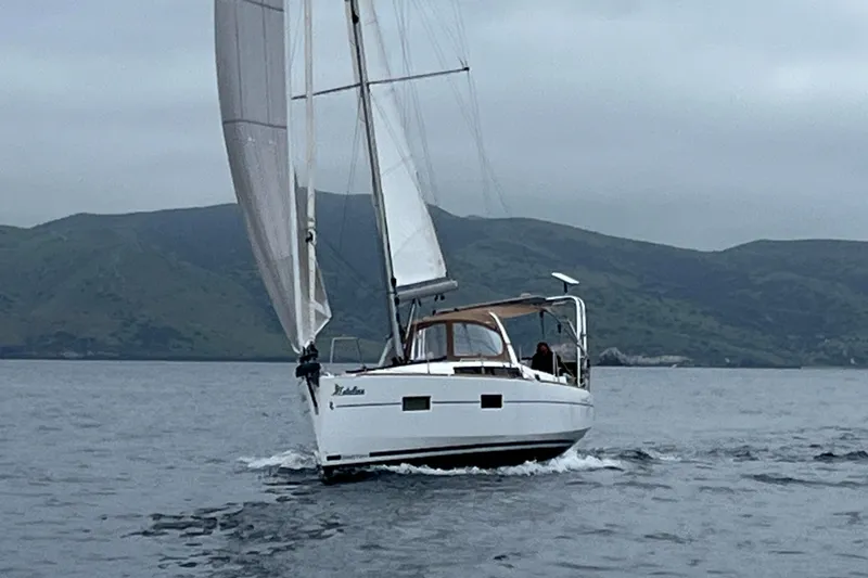 Slide: The Image of 2017 Beneteau Oceanis 38 sailing on calm waters with mountainous backdrop. - 3