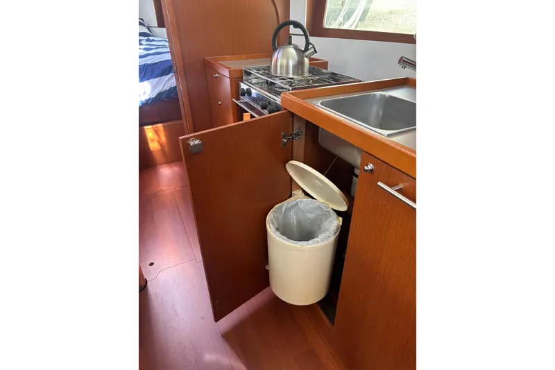 Slide: The Image of Interior of 2017 Beneteau Oceanis 38 yacht kitchen with sink, stove, and trash bin. - 45