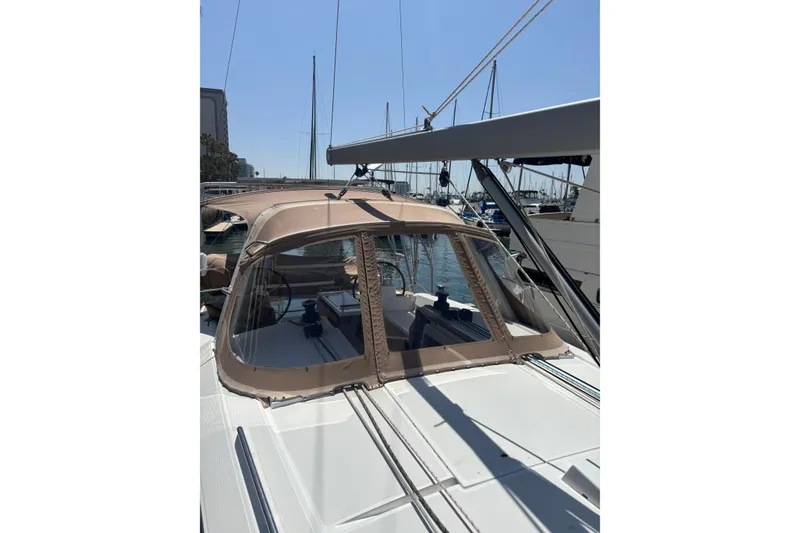 Slide: The Image of 2017 Beneteau Oceanis 38 sailboat with beige canopy, docked in a marina. - 55