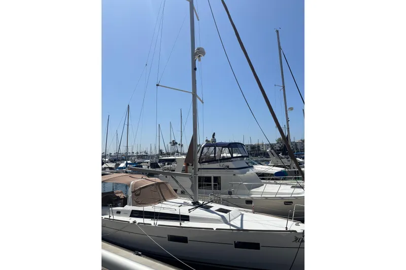 Slide: The Image of 2017 Beneteau Oceanis 38 sailboat docked in a sunny marina, surrounded by other boats. - 62