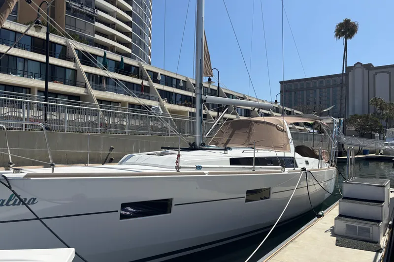 Slide: The Image of 2017 Beneteau Oceanis 38 sailboat docked at a marina, modern architecture in background. - 9