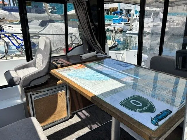 Slide: The Image of Interior of a Jeanneau NC 895 Offshore with table and seat, view of the marina. - 28