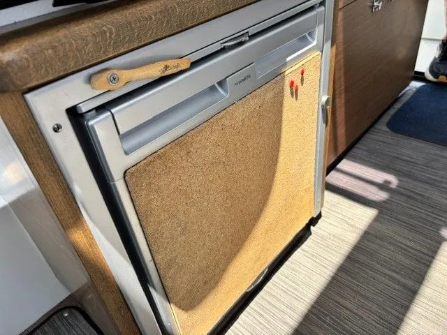 Slide: The Image of A refrigerator in a boat cabin with wood paneling and carpeted floor. - 22