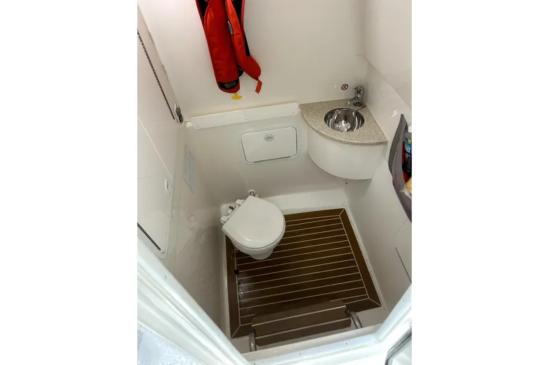 Slide: The Image of 2016 Regulator 28 Forward Seating boat bathroom with toilet, sink, and life jacket. - 15