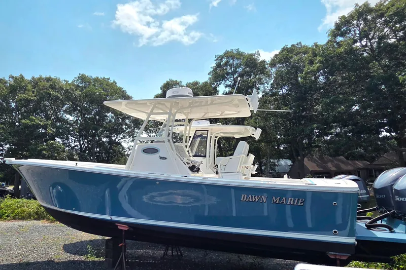 Slide: The Image of 2016 Regulator 28 Forward Seating boat, blue hull, named "Dawn Marie," on display outdoors. - 1