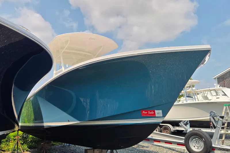 Slide: The Image of 2016 Regulator 28 Forward Seating boat for sale, blue hull, parked on trailer. - 2