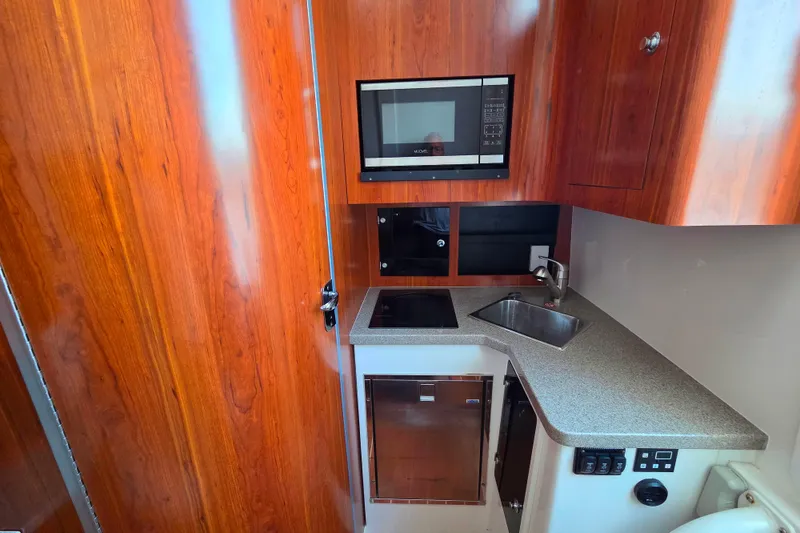 Slide: The Image of Compact kitchen area in a 2016 Regulator 41 boat with wood cabinetry and modern appliances. - 13