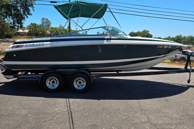 Slide: The Image of 1996 Cobalt 232 boat on trailer with green canopy, parked outdoors. - 1