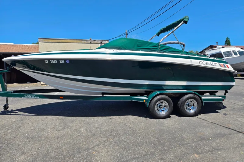Slide: The Image of 1996 Cobalt 232 boat on trailer, green and white, parked outdoors. - 10