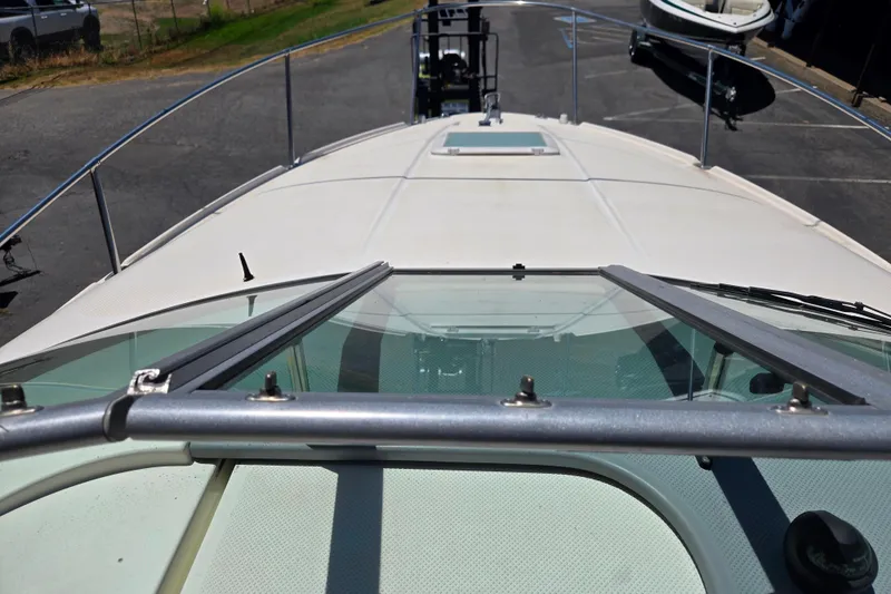 Slide: The Image of 2006 Bayliner 265 boat deck view with windshield and railing in a parking area. - 10