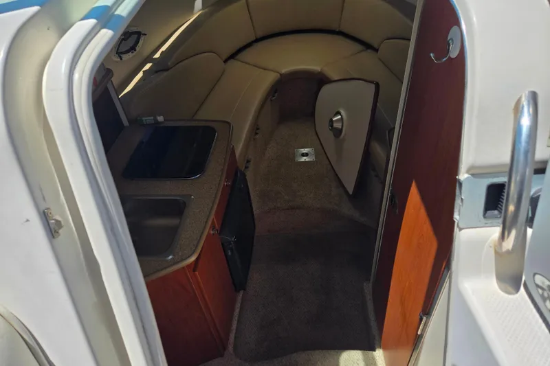 Slide: The Image of Interior of a 2006 Bayliner 265 boat, featuring a compact kitchenette and seating area. - 13