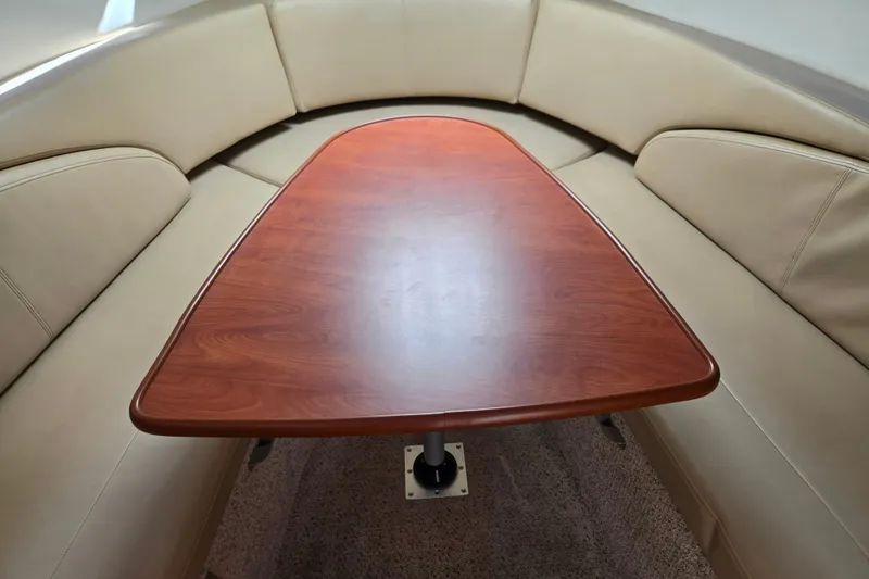 Slide: The Image of Interior of a 2006 Bayliner 265 boat with a wooden table and beige seating. - 14