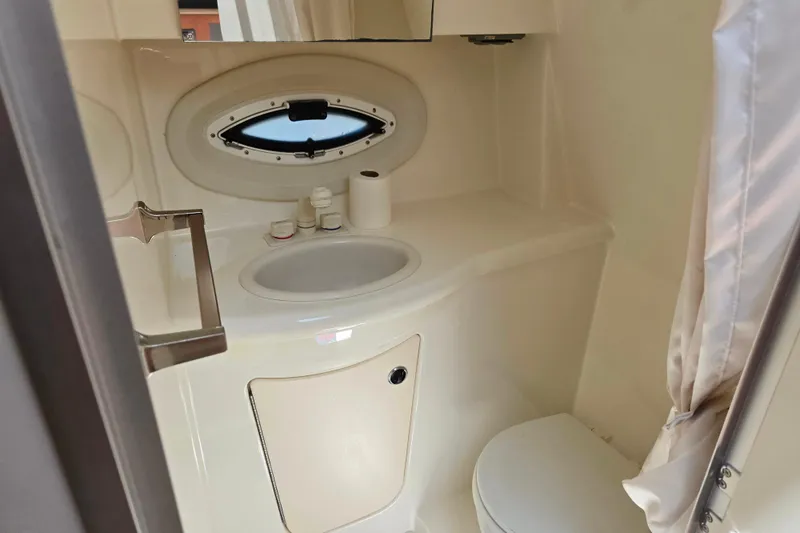 Slide: The Image of 2006 Bayliner 265 boat bathroom with sink, toilet, and porthole window. - 16