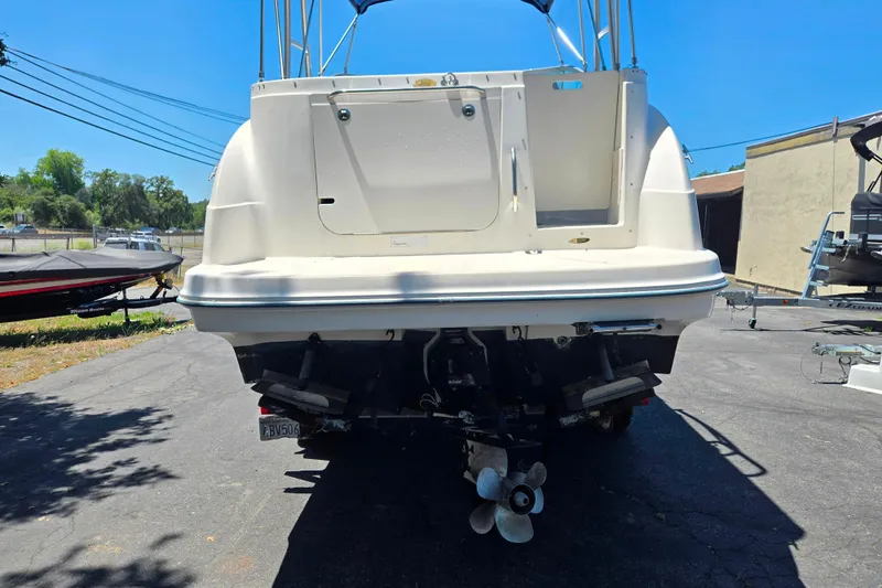 Slide: The Image of 2006 Bayliner 265 boat rear view, parked on pavement under clear blue sky. - 3