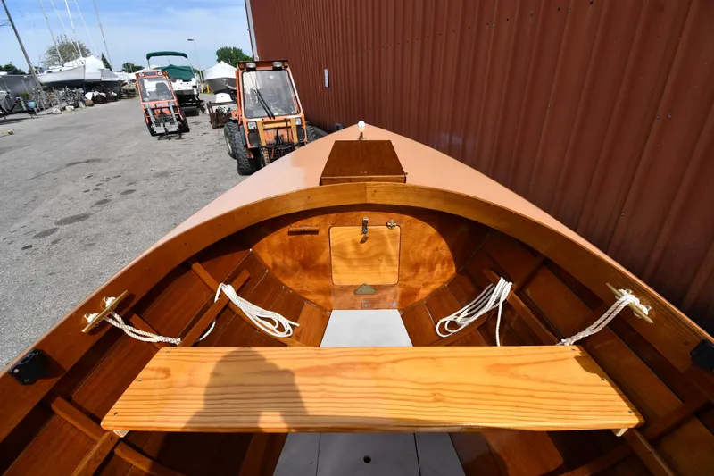 Slide: The Image of 2003 Great Lakes 16 Skiff boat interior with wooden seating and ropes, docked near tractors. - 15