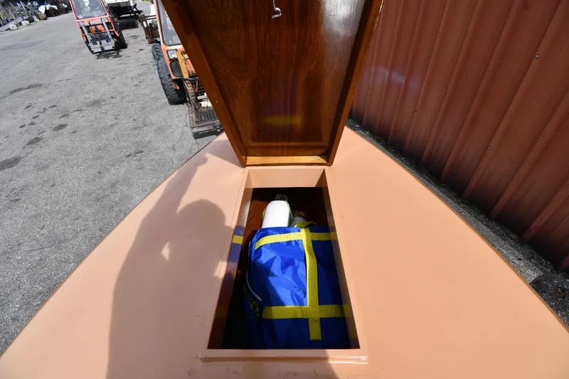 Slide: The Image of Open storage compartment on a 2003 Great Lakes 16 Skiff boat, revealing a blue and yellow bag. - 16