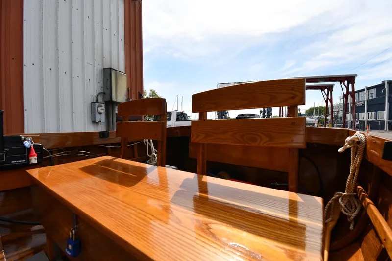Slide: The Image of 2003 Great Lakes 16 Skiff interior with polished wooden seats and table, dockside view. - 8