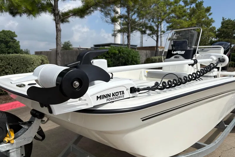 Slide: The Image of 2026 Mako Pro Skiff 17 CC with Minn Kota PowerDrive trolling motor, parked outdoors. - 1