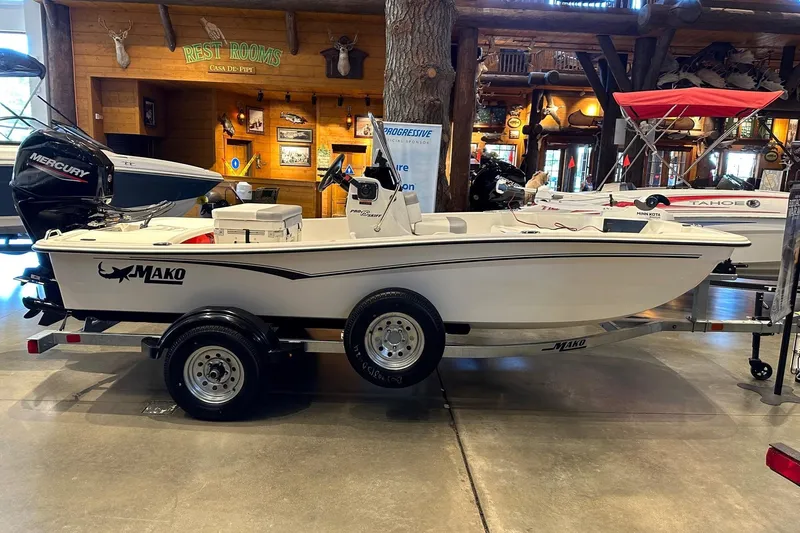 Slide: The Image of 2026 Mako Pro Skiff 15 CC boat displayed indoors on a trailer. - 1