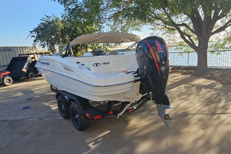 Slide: The Image of 2026 Tahoe 1950 boat with outboard motor on trailer, parked near a lake. - 7