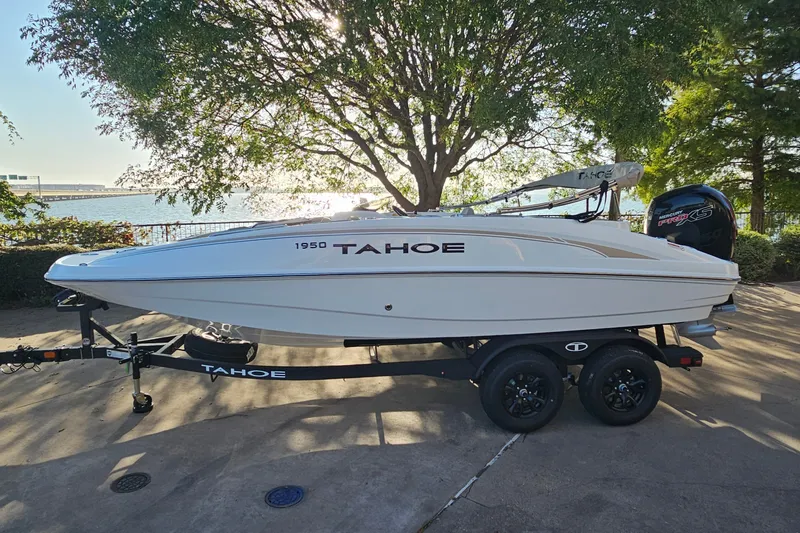 The Image of 2026 Tahoe 1950 boat on trailer by lakeside, surrounded by trees. - 0