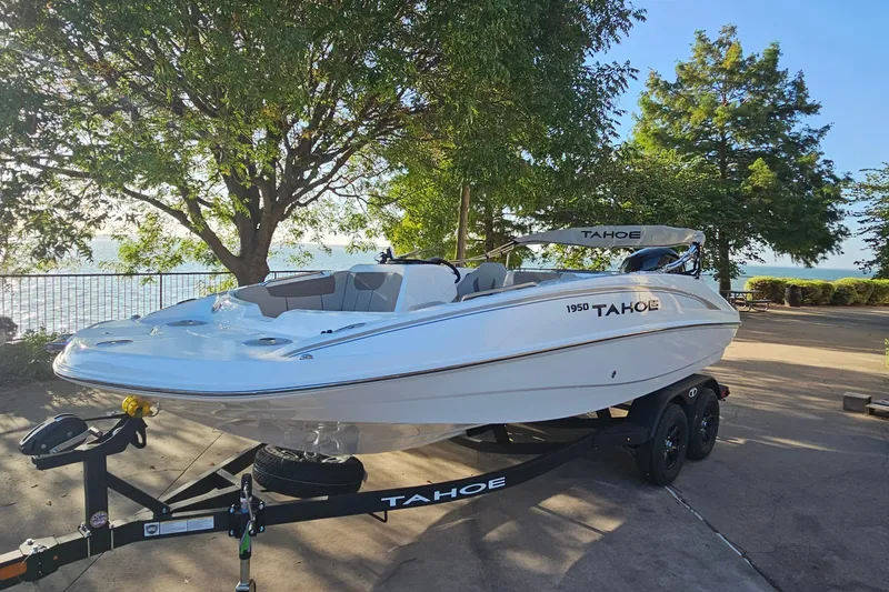 Slide: The Image of 2026 Tahoe 1950 boat on trailer by lakeside, surrounded by trees. - 1