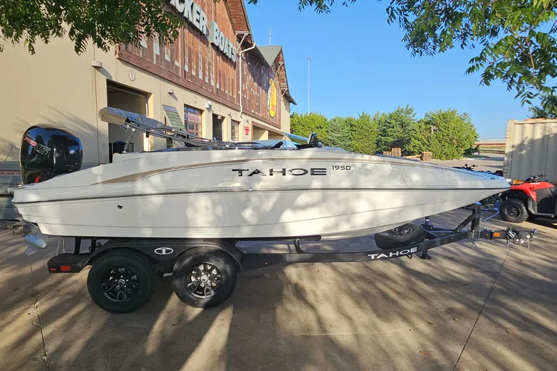 Slide: The Image of 2026 Tahoe 1950 boat on trailer outside a dealership, under clear blue sky. - 4