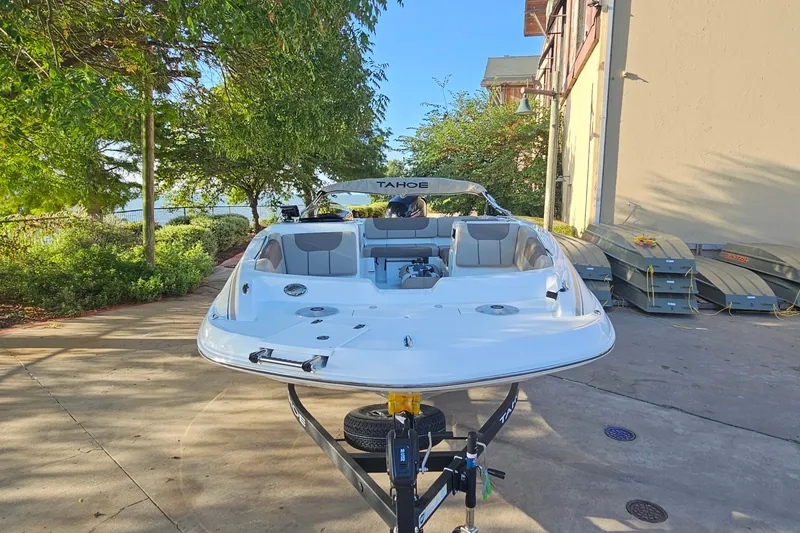 Slide: The Image of 2026 Tahoe 1950 boat on trailer, parked outdoors near trees and building. - 2
