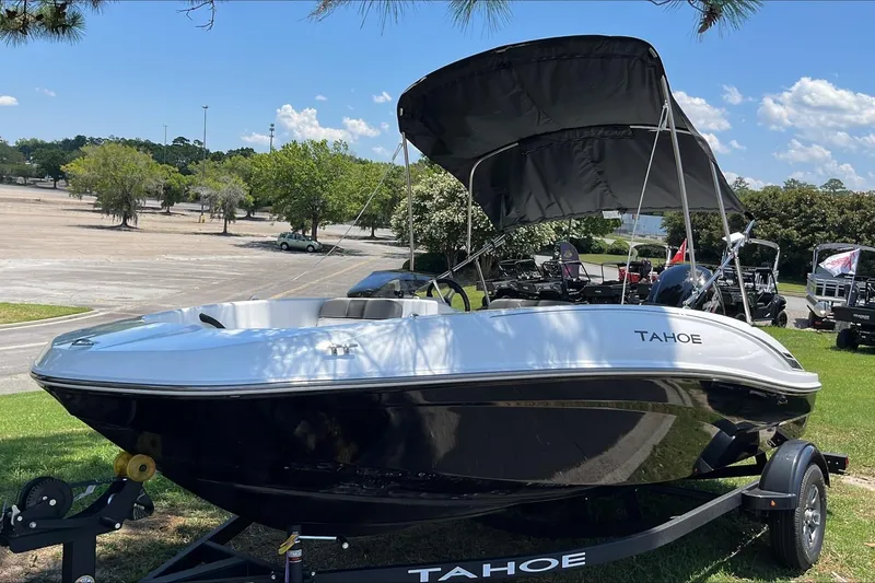 Slide: The Image of 2026 Tahoe T16 boat with canopy on trailer, parked outdoors under clear sky. - 1