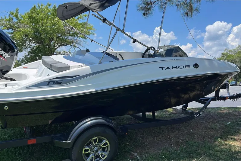 Slide: The Image of 2026 Tahoe T16 boat on trailer, parked outdoors under a sunny sky. - 2