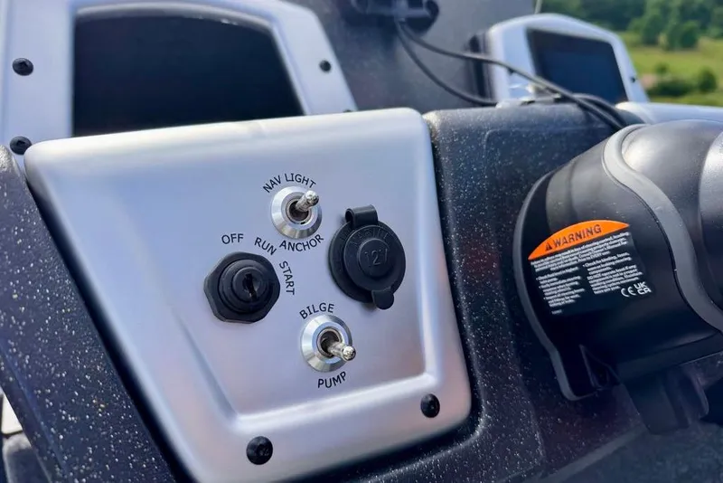Slide: The Image of Control panel of 2026 Tracker Pro Team 195 boat with switches and warning label. - 11