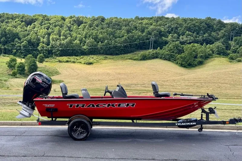 The Image of 2026 Tracker Pro Team 195 boat on trailer, set against a scenic countryside backdrop. - 0