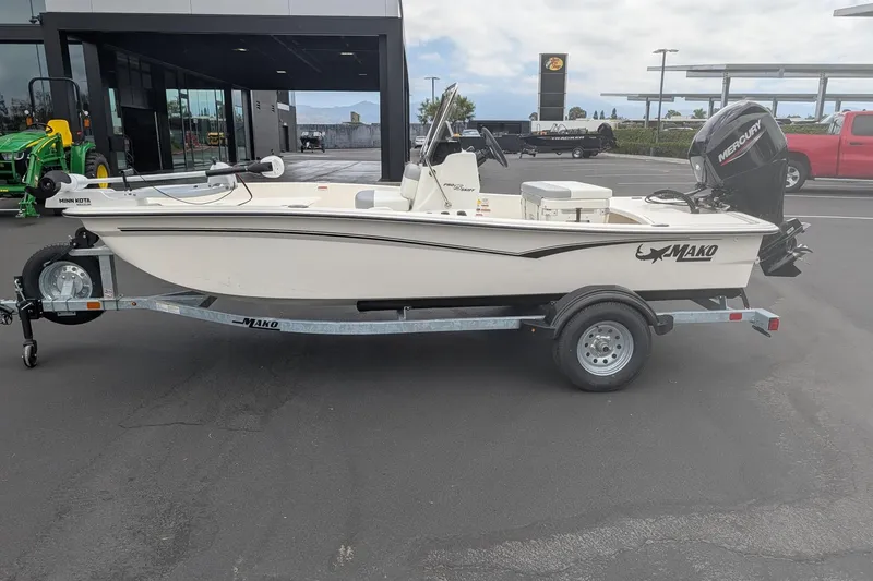 Slide: The Image of 2026 Mako Pro Skiff 15 CC boat on trailer, parked outdoors near dealership. - 1