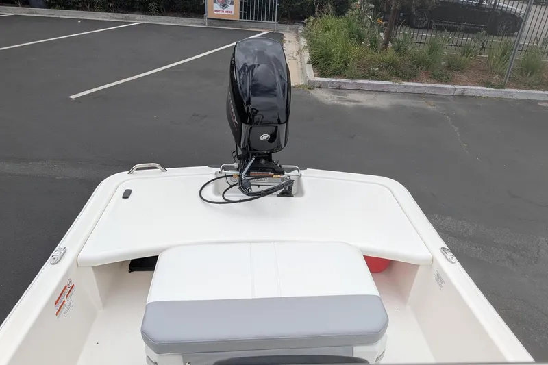 Slide: The Image of 2026 Mako Pro Skiff 15 CC boat with outboard motor in a parking lot. - 10